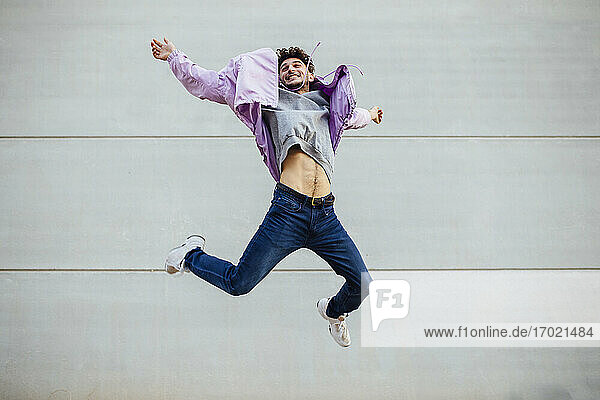 Happy man jumping against gray wall
