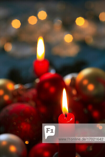 Red burning advent candles and Christmas baubles