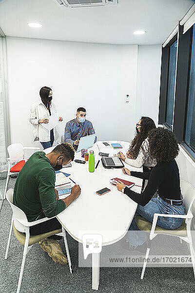 Kreative männliche und weibliche Kollegen diskutieren  während sie im Sitzungssaal im Büro sitzen