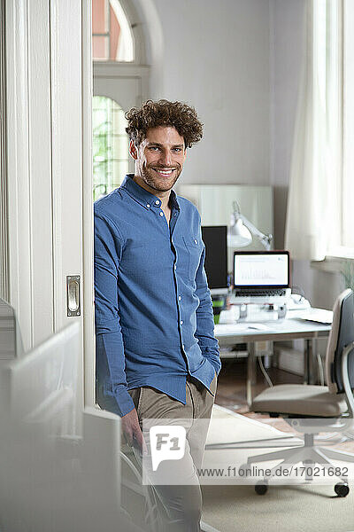 Smiling male professional with hand in pocket at office