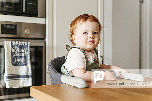 Porträt eines kleinen Mädchens  das am Küchentisch sitzt