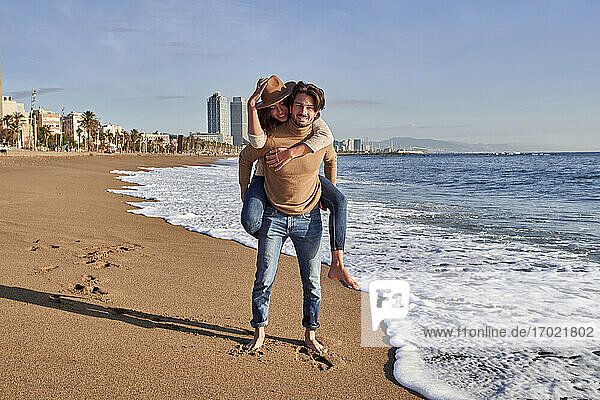 Boyfriend piggybacking girlfriend while standing on beach