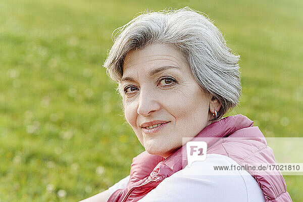 Lächelnde reife Frau mit grauem Haar in einem öffentlichen Park