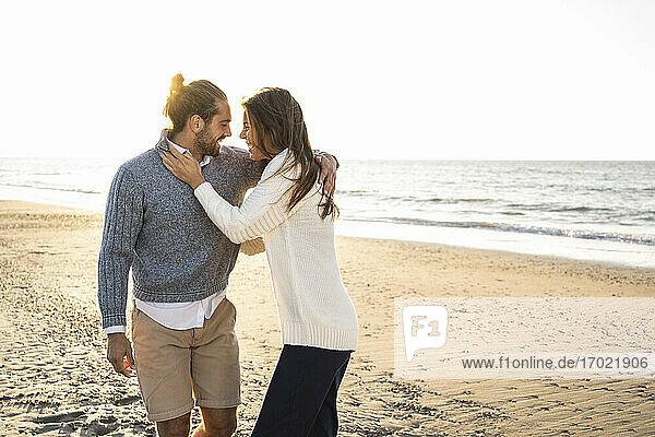 Glückliches junges Paar umarmt am Strand während eines sonnigen Tages