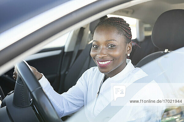 Lächelnde Frau hält das Lenkrad  während sie im Auto sitzt
