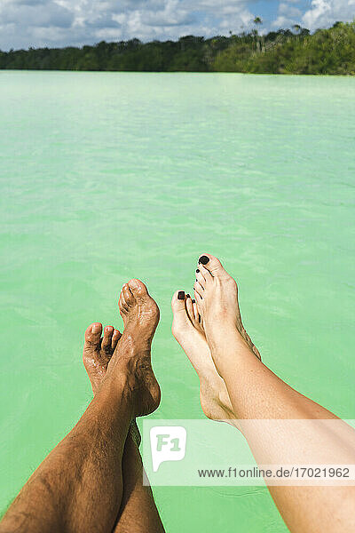 Heterosexuelles Paar Beine über Meer an sonnigem Tag