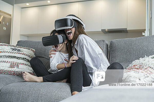 Aufgeregte Mutter und Tochter verwenden Virtual-Reality-Brille zu Hause