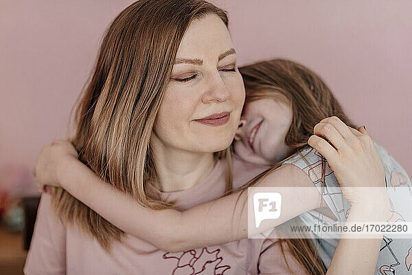 Daughter embracing mother against wall at home