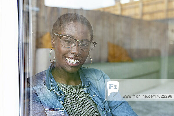Lächelnde Frau schaut durch ein Fenster