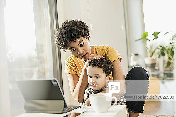 Mutter und Sohn sehen zu Hause auf einem digitalen Tablet zu