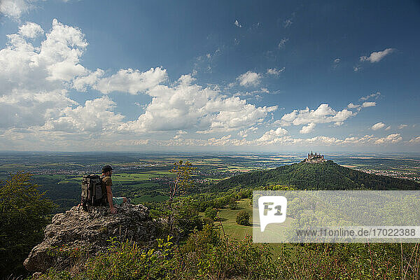 Wanderer mit Blick auf die Burg Hohenzollern  sitzend auf einem Berg auf der Schwäbischen Alb  Deutschland