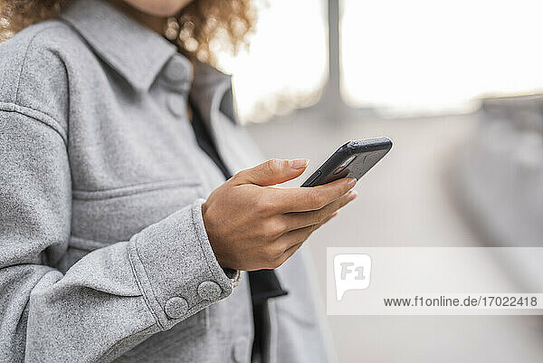 Junge Frau  die ihr Smartphone benutzt  während sie auf einer Brücke in der Stadt steht