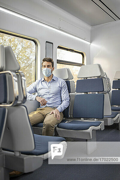 Businessman wearing protective face sitting in train during COVID-19