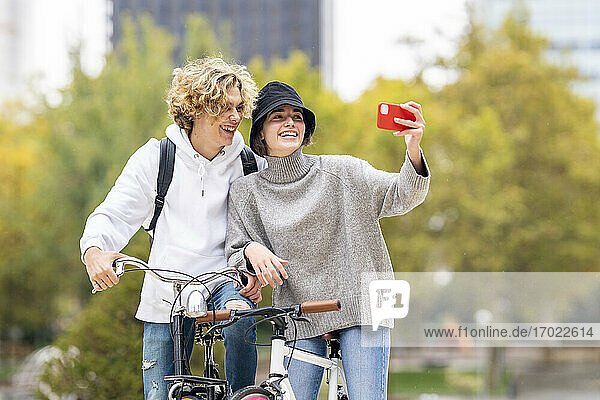 Freunde lachen  während sie im Park ein Selfie mit dem Handy machen