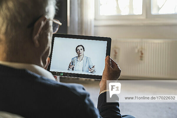 Ärztin berät männlichen Patienten per Videoanruf über ein digitales Tablet zu Hause