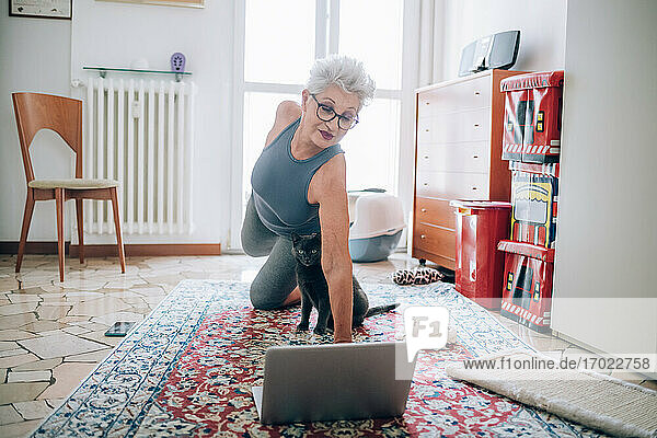 Woman following online yoga class with her cat