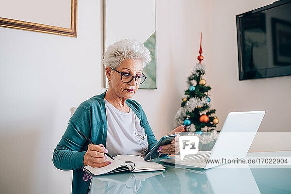 Frau arbeitet von zu Hause aus  Weihnachtsbaum im Hintergrund