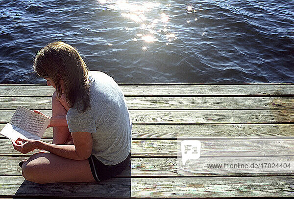 Woman reading on dock by lake