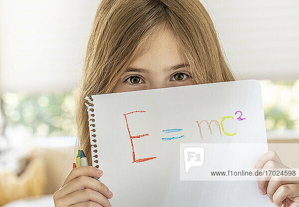 Mädchen (8-9) hält Papier mit Emc2-Formel vor das Gesicht