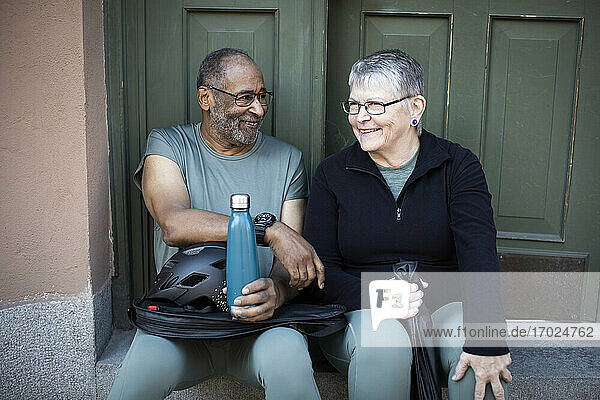 Lächelndes Paar  das an der Tür eines Hauses sitzt