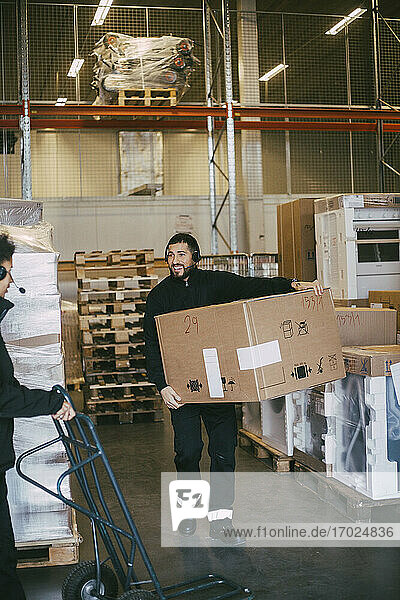 Männlicher Unternehmer trägt Box-Container im Auslieferungslager