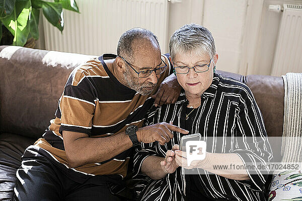 Älteres Paar verwendet Smartphone im Wohnzimmer