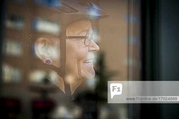 Lächelnde Seniorin durch Fenster zu Hause gesehen