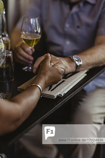 Ausgeschnittenes Bild von Paar hält Hände über Tisch in Café