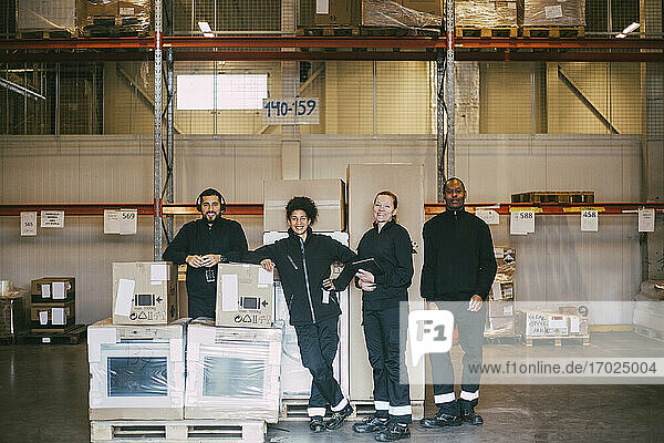 Portrait of smiling warehouse workers standing with box containers