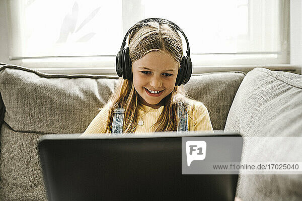 Lächelndes Mädchen studiert auf Laptop zu Hause