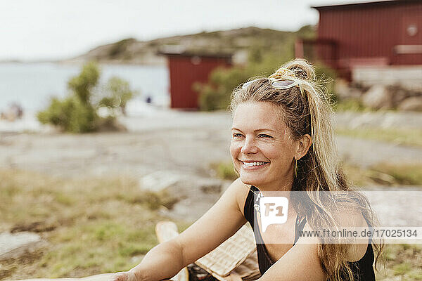 Lächelnde Frau schaut beim Picknick am Hafen weg