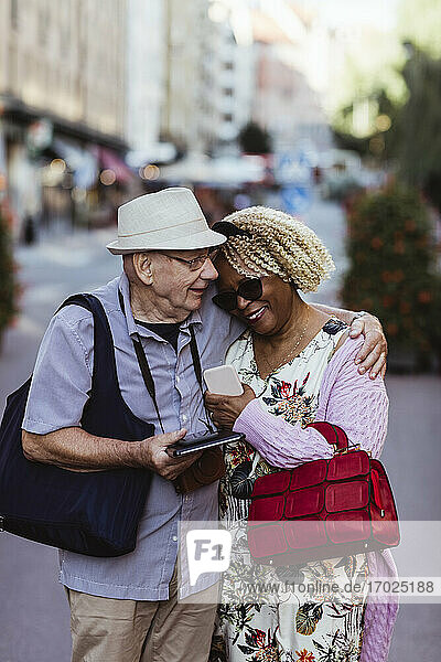Senior Mann umarmt Frau  während auf der Straße in der Stadt stehen