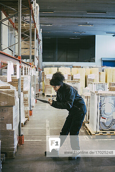 Female manual worker analyzing box containers at distribution warehouse