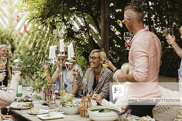 Fröhliche Familie mit Trinkspruch mit Weinglas beim Abendessen Partei im Vorgarten