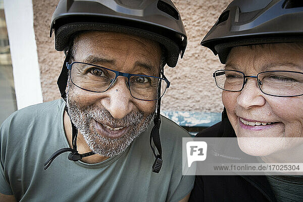 Lächelndes Paar mit Fahrradhelm vor dem Haus