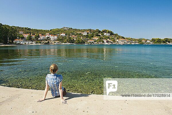 Photo of a tourist on Kolocep Island (Kalamota)  Elaphiti Islands  Dalmatian Coast  Croatia. This photo shows a tourist visiting Kolocep Island in the Elaphiti Islands. The Elaphiti Islands are a small archipelago situated just a short boat crossing from Dubrovnik on the Dalmatian Coast of Croatia. Kolocep (Kalamota) has two small villages  each with their own port and  unlike many islands along the Dalmatian Coast  Kolocep (Kalamota) is host to a long sandy beach.