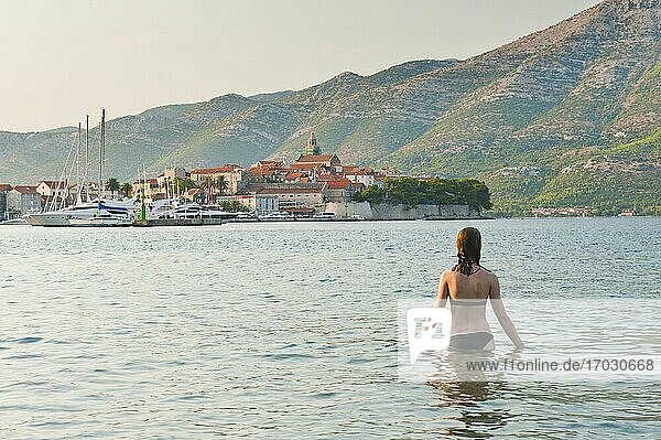 Weibliche Touristin beim Schwimmen im Stadthafen von Korcula  Insel Korcula  Dalmatien (Dalmacija)  Kroatien. Dies ist ein Foto einer weiblichen Touristin  die im Hafen von Korcula-Stadt ein Sonnenbad nimmt. Die Stadt Korcula ist der Hauptort auf der Insel Korcula an der dalmatinischen Küste (Dalmacija) in Kroatien.