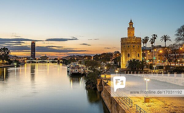 Boardwalk at the river Rio Guadalquivir with illuminated Torre del Oro  in the back Torre Sevilla  sunset  blue hour  Sevilla  Andalusia  Spain  Europe