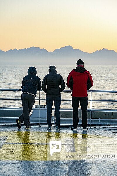 Passengers looking over the ocean  evening mood on the ferry in front of silhouette of mountains  Lofoten  Nordland  Norway  Europe