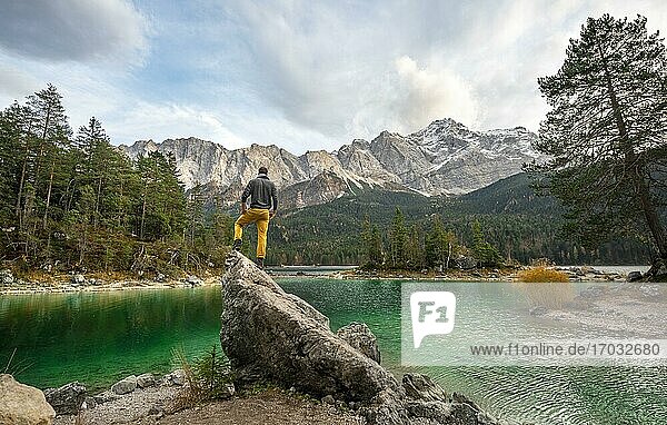 Young man standing on a rock on the shore  view into the distance  Eibsee lake in front of Zugspitze massif with Zugspitze  Wetterstein range  near Grainau  Upper Bavaria  Bavaria  Germany  Europe