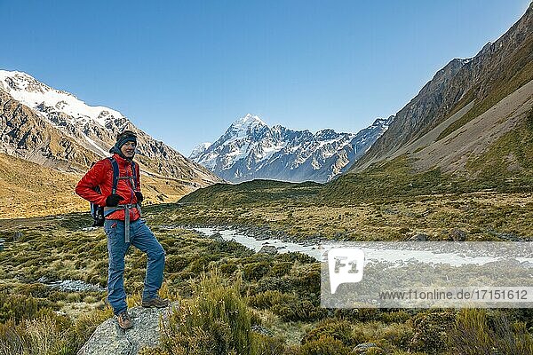 Hiker standing on a rock  Hooker Valley overlooking snow-capped Mount Cook  Hooker River  snow-capped Mount Cook National Park  Southern Alps  Canterbury  South Island  New Zealand  Oceania