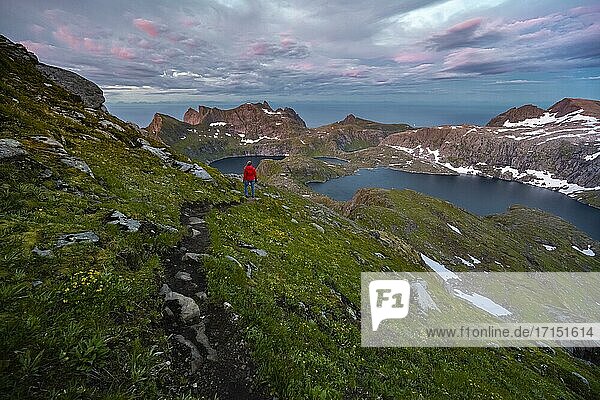 Sonnenuntergang mit dramatischen Wolken  Wanderin auf Wanderung zum Hermannsdalstinden  Seen Krokvatnet und Tennesvatnet  Berge  Moskenesøya  Lofoten  Nordland  Norwegen  Europa