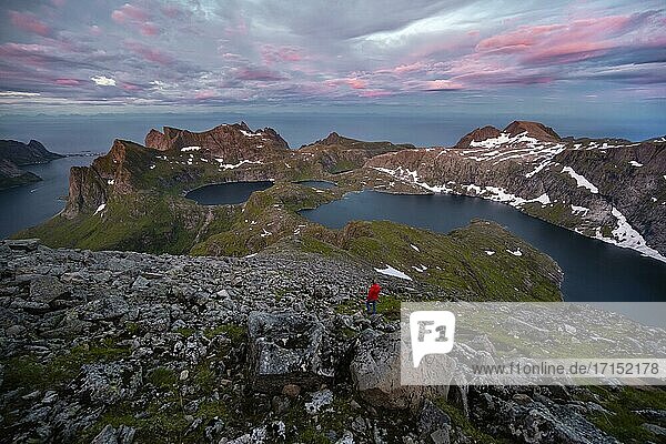 Sonnenuntergang mit dramatischen Wolken  Wanderin auf Wanderung zum Hermannsdalstinden  Seen Krokvatnet und Tennesvatnet  Berge  Moskenesøya  Lofoten  Nordland  Norwegen  Europa