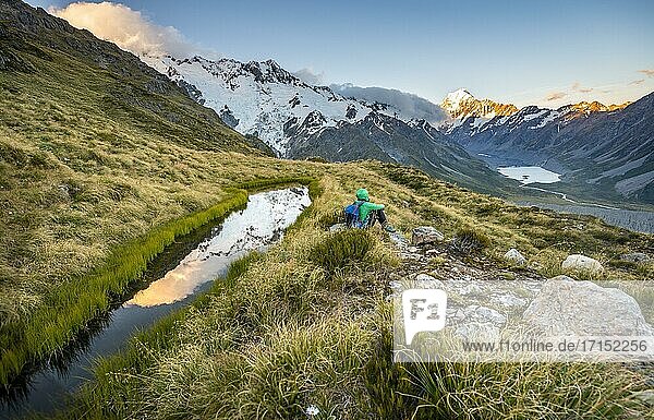 Hiker sitting at a mountain lake  View of Hooker Valley with Hooker Lake and Mount Cook  Sealy Tarns at sunset  Hooker Valley  Mount Cook National Park  Southern Alps  Canterbury  South Island  New Zealand  Oceania
