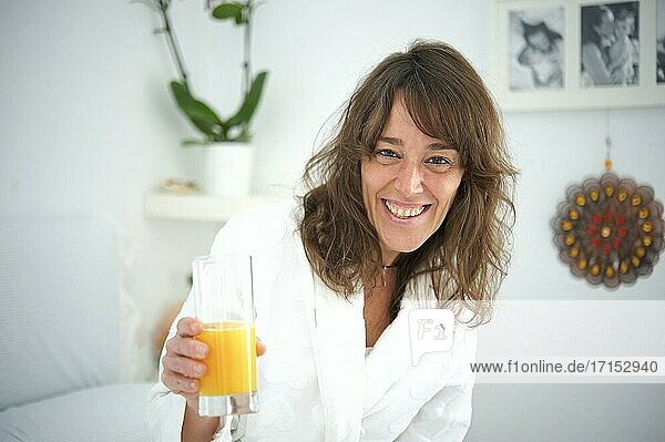 Frau beim Frühstück im Bett mit Orangensaft.