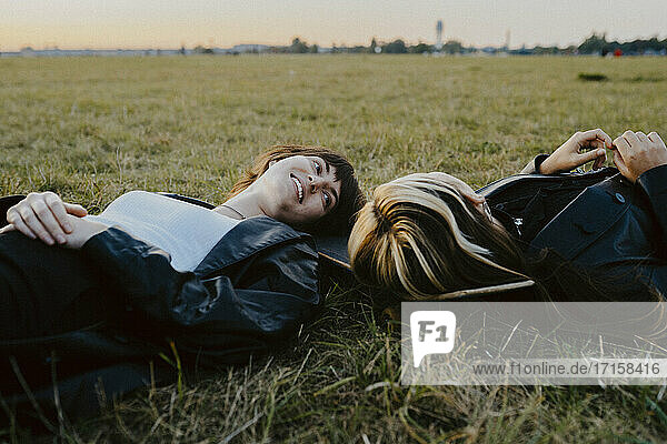 Young female friends lying down on grass in park