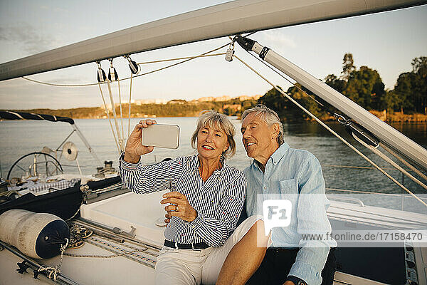 Lächelnde ältere Paar unter Selfie auf Smartphone  während in Boot sitzen