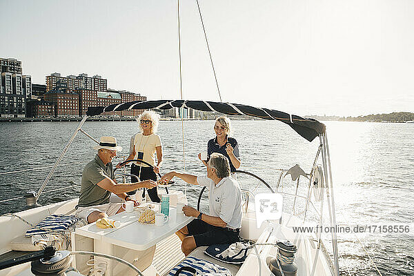 Senior couples having food while sitting in boat against clear sky