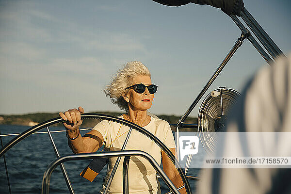 Ältere Frau schaut weg  während Segelboot gegen Himmel auf sonnigen Tag