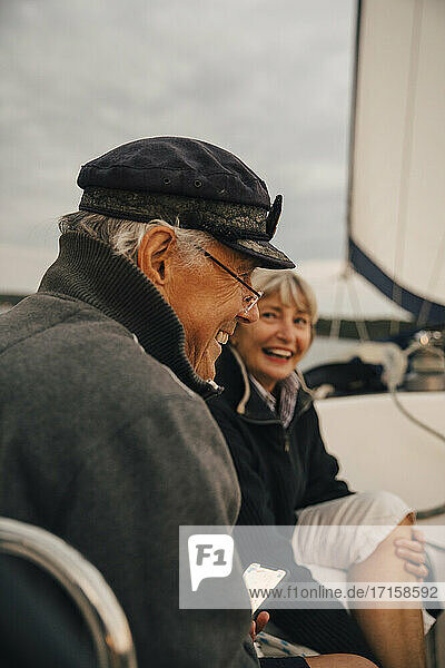 Fröhliche ältere Paar lachen  während im Gespräch mit einander auf Boot während des Sonnenuntergangs